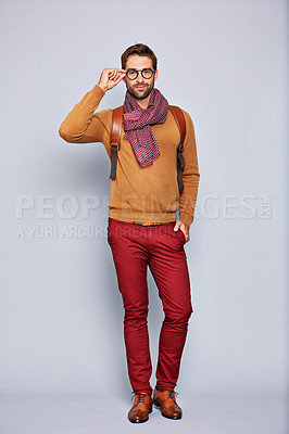 Buy stock photo Studio portrait of a handsome young man adjusting his glasses against a grey background