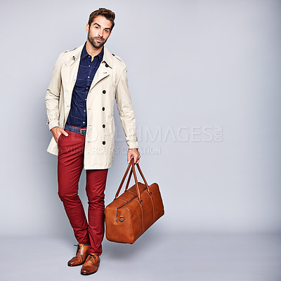 Buy stock photo Studio portrait of a handsome young man carrying a suitcase against a grey background