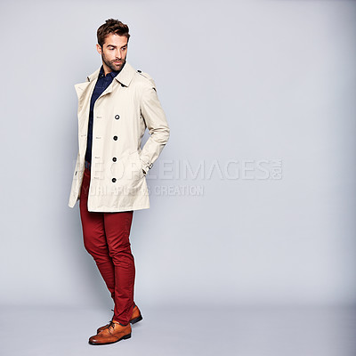 Buy stock photo Studio shot of a handsome young man posing in a trench coat against a grey background