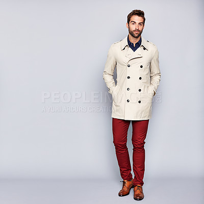 Buy stock photo Studio portrait of a handsome young man posing in a trench coat against a grey background