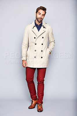 Buy stock photo Studio portrait of a handsome young man posing in a trench coat against a grey background