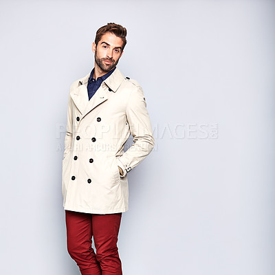 Buy stock photo Studio portrait of a handsome young man posing in a trench coat against a grey background