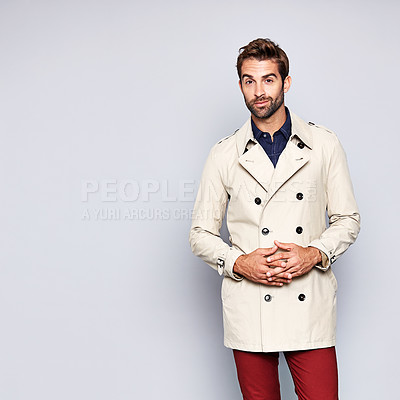 Buy stock photo Studio portrait of a handsome young man posing in a trench coat against a grey background