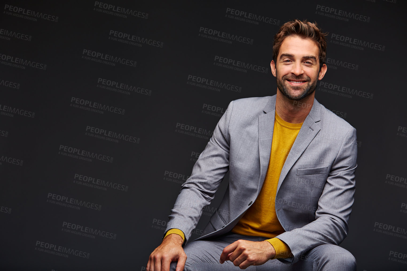 Buy stock photo Studio portrait of a handsome young businessman sitting against a grey background