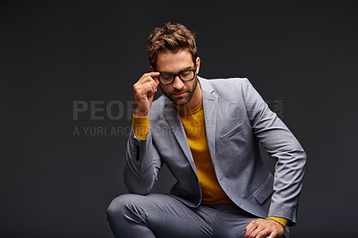 Buy stock photo Studio shot of a handsome young businessman sitting against a grey background