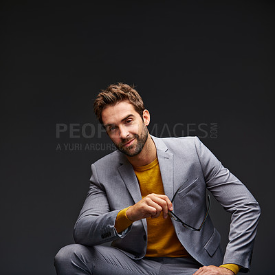 Buy stock photo Studio portrait of a handsome young businessman sitting against a grey background
