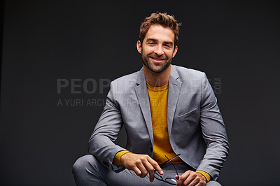 Buy stock photo Studio portrait of a handsome young businessman sitting against a grey background