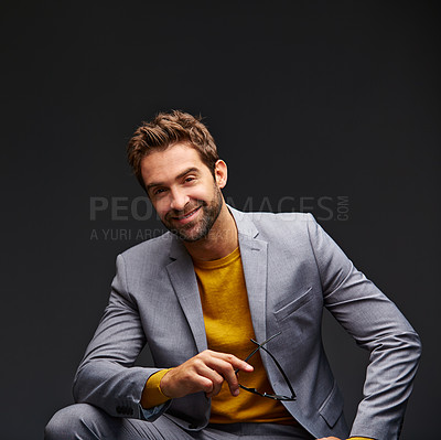 Buy stock photo Studio portrait of a handsome young businessman sitting against a grey background
