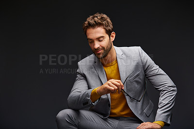 Buy stock photo Studio shot of a handsome young businessman sitting against a grey background