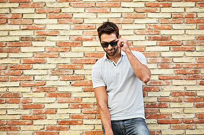 Buy stock photo Shot of a man talking on his cellphone while leaning against a brick wall