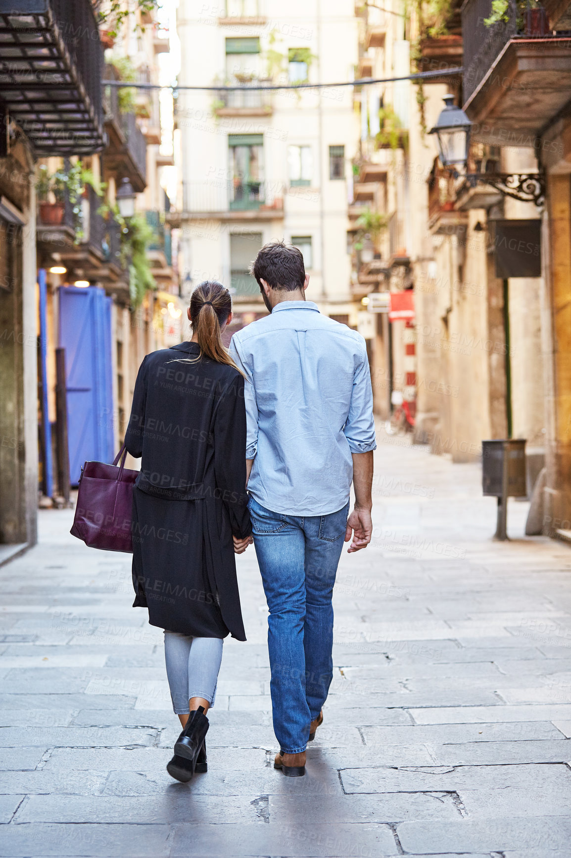 Buy stock photo Back view, walking and couple in city for travel, bonding and relationship trip for anniversary. Man, woman and holding hands in town for exploring, together and care with connection outdoor on tour