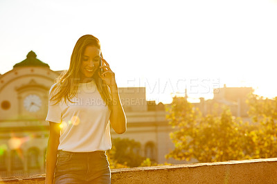 Buy stock photo Shot of a woman talking on her cellphone while standing on a rooftop