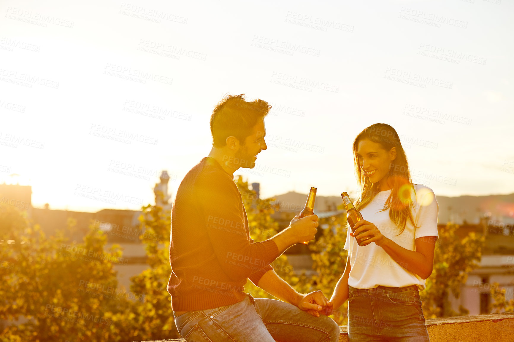 Buy stock photo Beer, sunset and toast with couple on rooftop together for celebration, date or romance. Cheers, flare and smile of excited people drinking alcohol outdoor in city for bonding, love or milestone