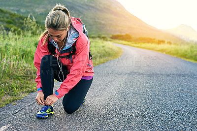 Buy stock photo Full length shot of an attractive young female athlete tying her laces before a morning run