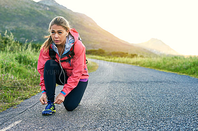 Buy stock photo Full length shot of an attractive young female athlete tying her laces before a morning run