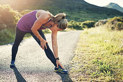 Buy stock photo Full length shot of an attractive young female athlete stretching before her morning run