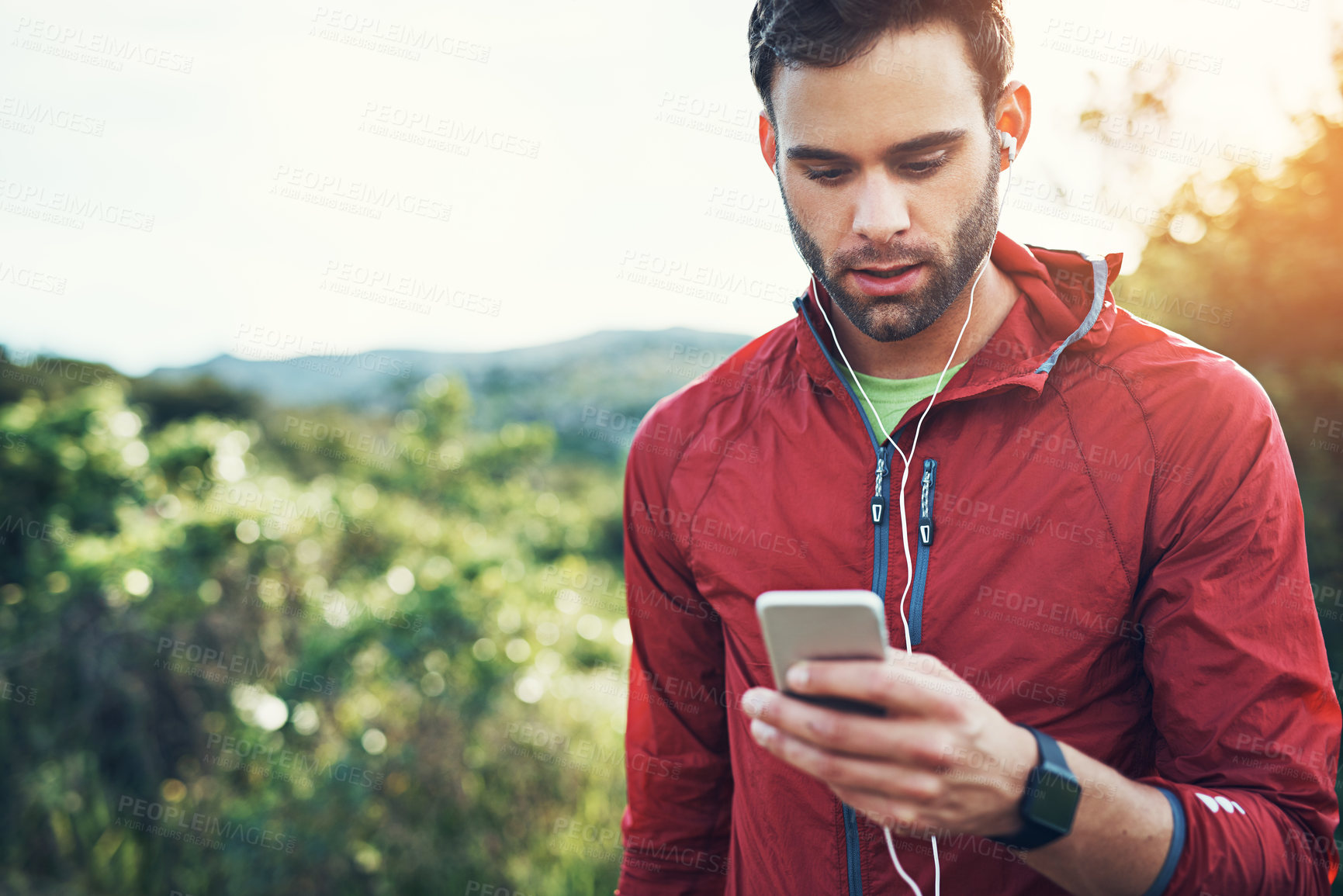 Buy stock photo Cropped shot of a handsome young male athlete checking his cellphone while out for a morning run