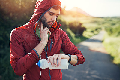 Buy stock photo Cropped shot of a handsome young male athlete tracking his pulse while out for a morning run