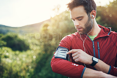 Buy stock photo Cropped shot of a handsome young male athlete preparing his playlist while out for a morning run