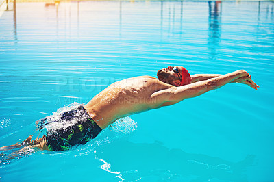 Buy stock photo Shot of a handsome young male swimmer doing backstroke in a swimming pool