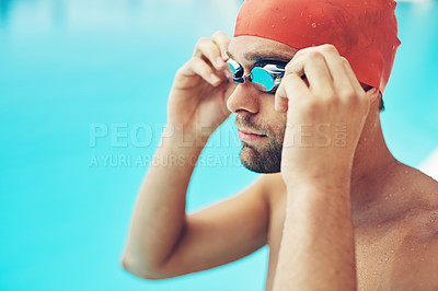 Buy stock photo Cropped shot of a handsome young male swimmer adjusting his goggles before a swim