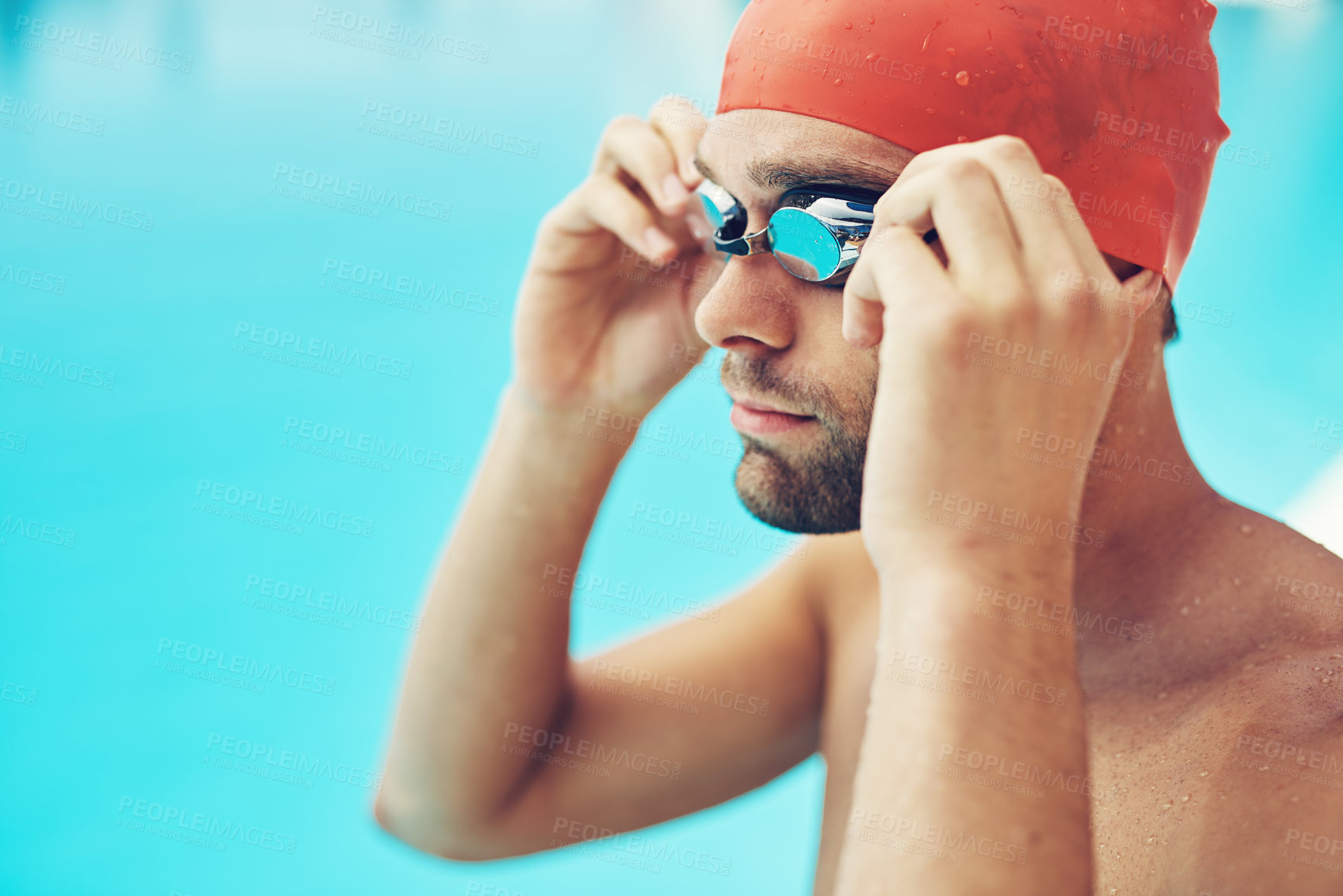 Buy stock photo Cropped shot of a handsome young male swimmer adjusting his goggles before a swim