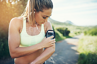 Buy stock photo Cropped shot of an attractive young female athlete preparing her playlist while out for a morning run