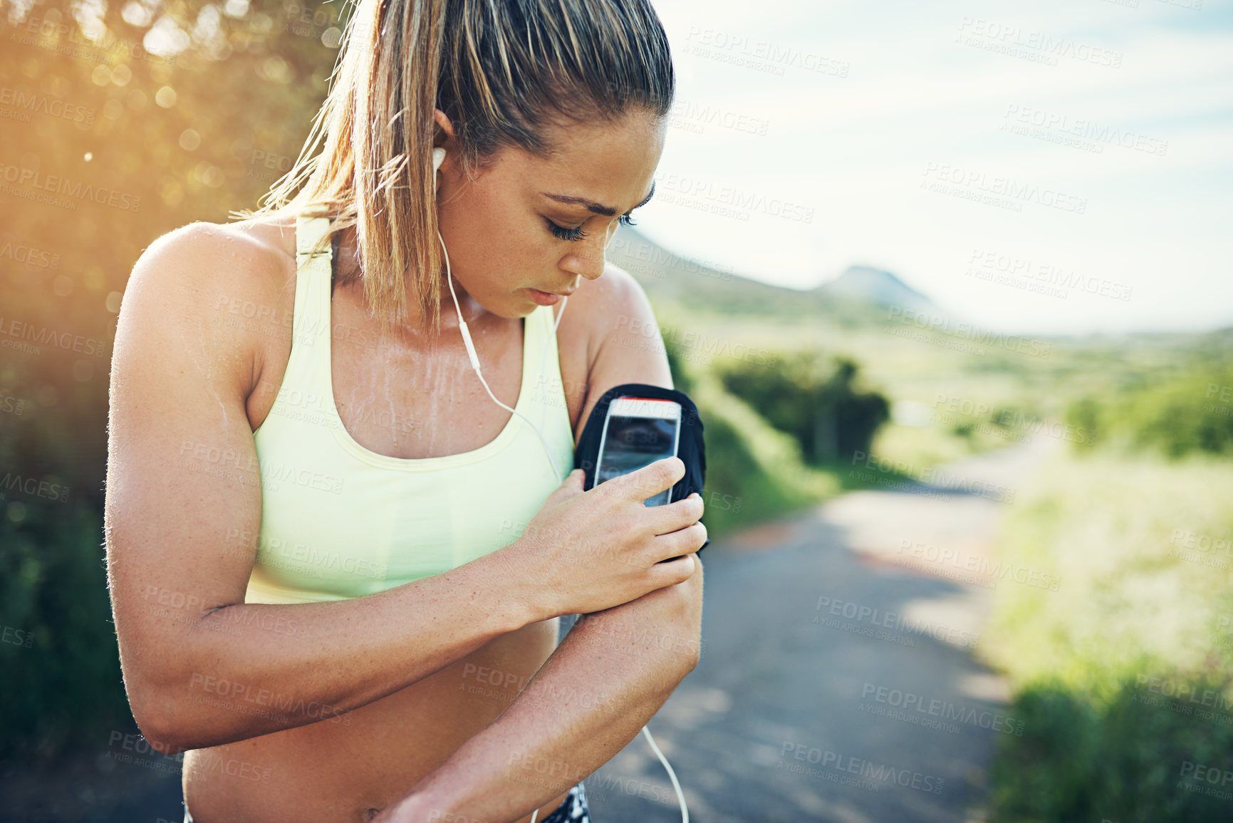 Buy stock photo Cropped shot of an attractive young female athlete preparing her playlist while out for a morning run
