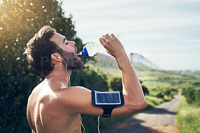 Buy stock photo Cropped shot of a handsome young male athlete drinking water while out for his morning run