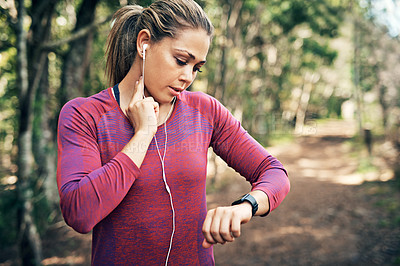 Buy stock photo Cropped shot of an attractive young female athlete tracking her pulse while out for a morning run