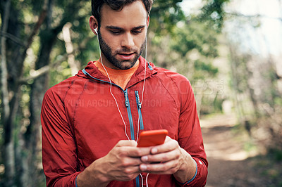 Buy stock photo Cropped shot of a handsome young male athlete checking his messages while out for a morning run