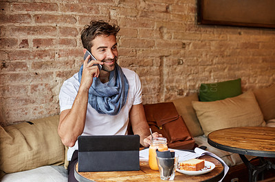 Buy stock photo Shot of a handsome young man using his digital tablet while sitting in a cafe