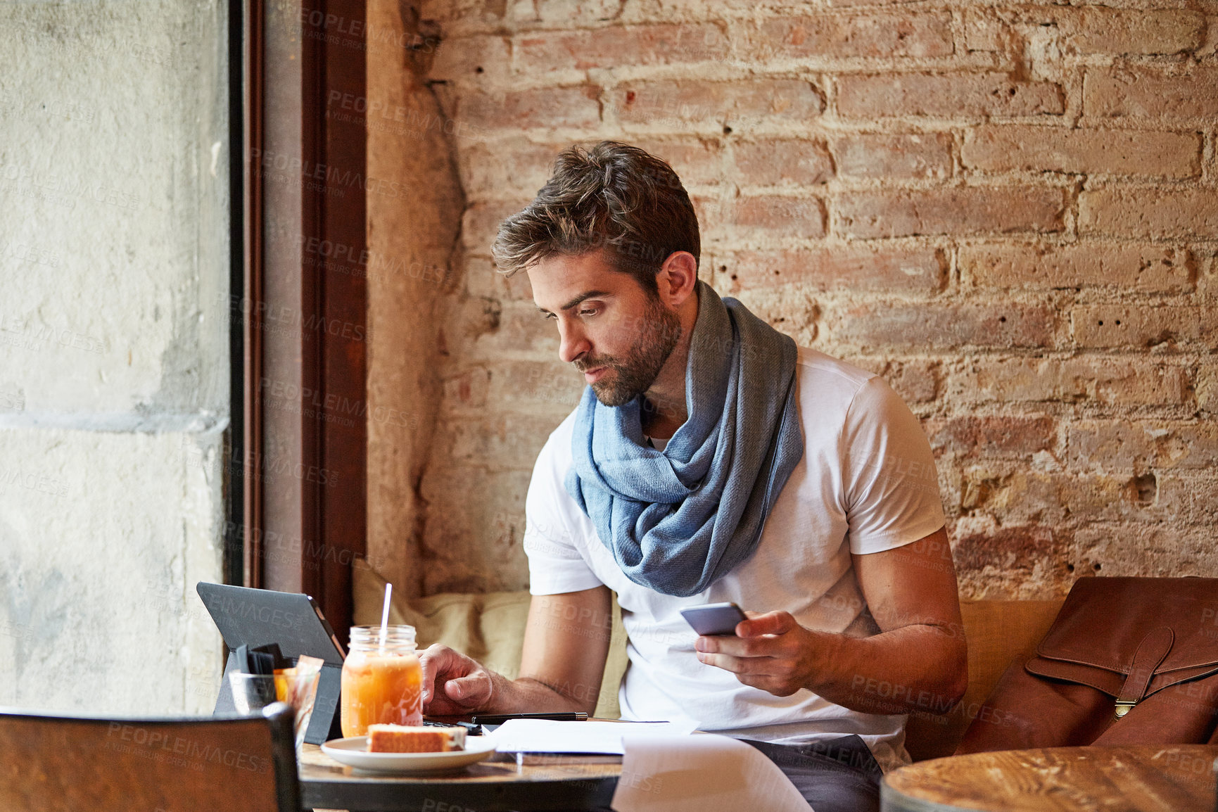 Buy stock photo Shot of a customer using his cellphone and digital tablet in a cafe