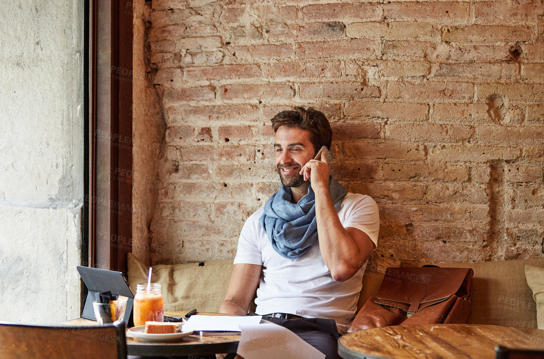 Buy stock photo Shot of a handsome young man using his cellphone while sitting in a cafe