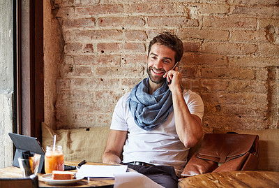 Buy stock photo Shot of a handsome young man using his cellphone while sitting in a cafe