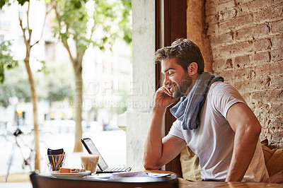 Buy stock photo Shot of a handsome young man using his cellphone while sitting in a cafe