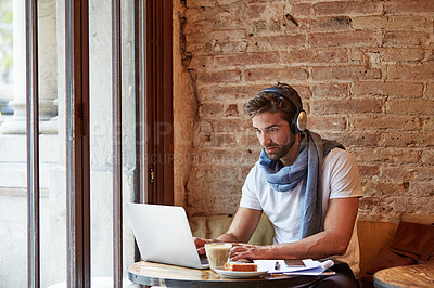 Buy stock photo Shot of a young man working on his laptop while sitting in a cafe