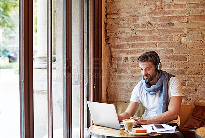 Buy stock photo Shot of a young man working on his laptop while sitting in a cafe