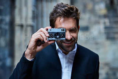 Buy stock photo Cropped shot of a handsome young businessman taking pictures while standing in an urban alleyway