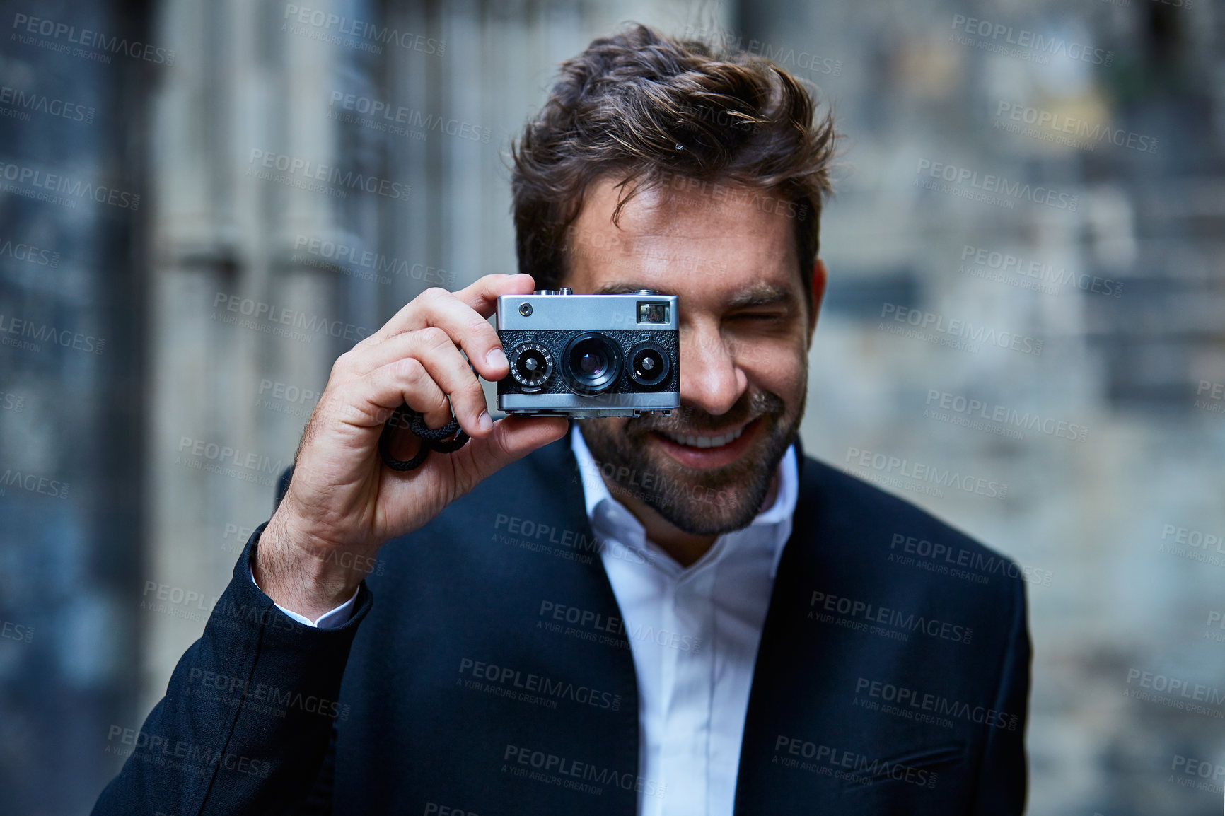 Buy stock photo Cropped shot of a handsome young businessman taking pictures while standing in an urban alleyway