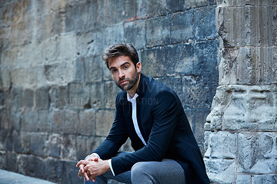 Buy stock photo Cropped portrait of a handsome young businessman sitting in an urban alleyway