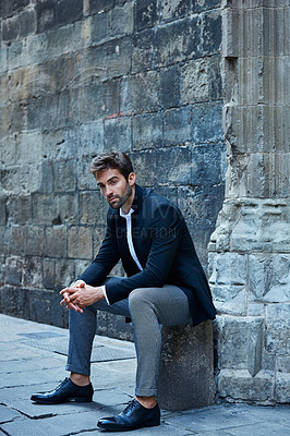 Buy stock photo Full length shot of a handsome young businessman sitting in an urban alleyway