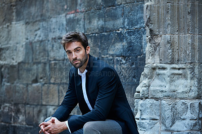Buy stock photo Cropped portrait of a handsome young businessman sitting in an urban alleyway