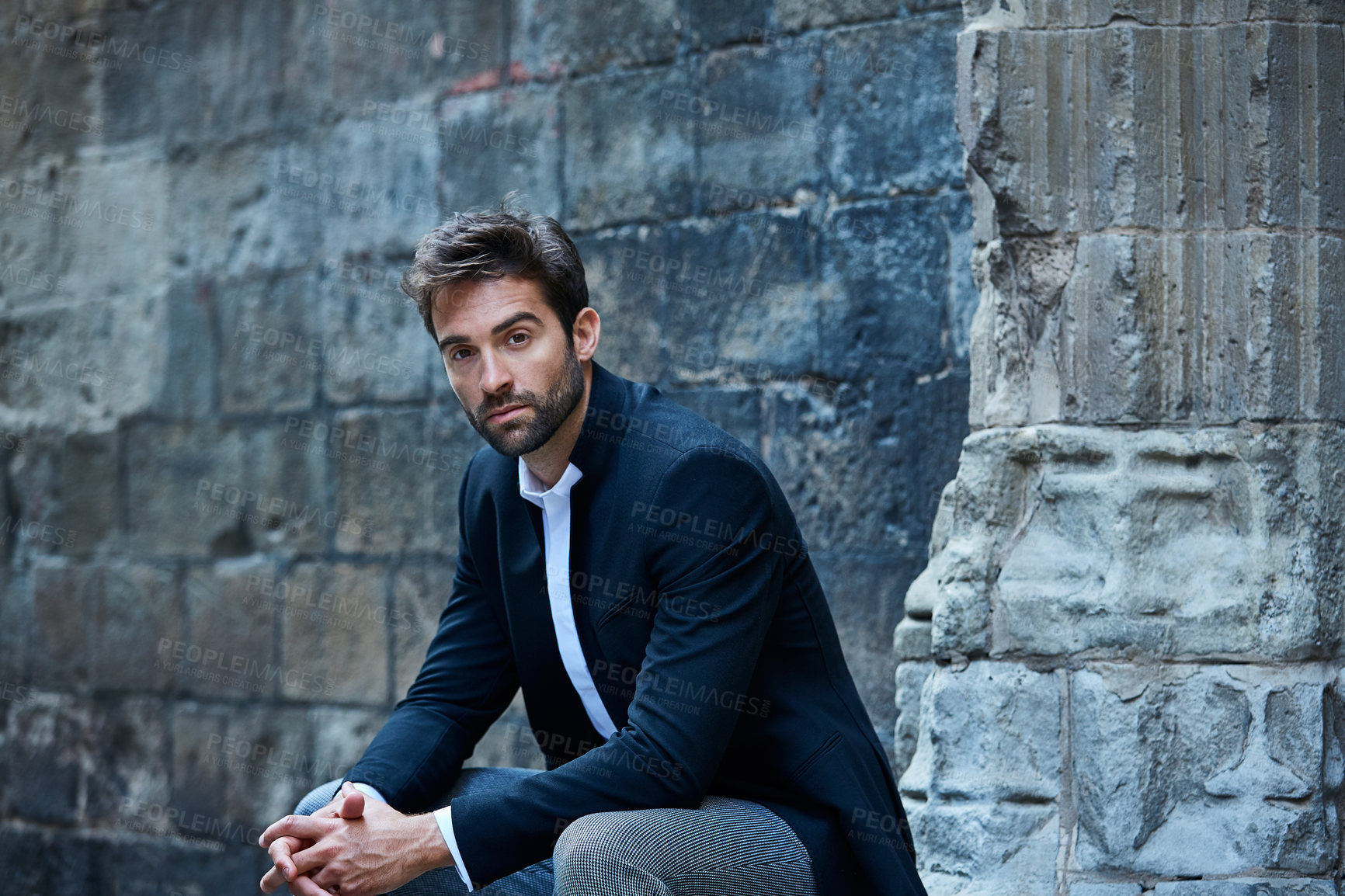 Buy stock photo Cropped portrait of a handsome young businessman sitting in an urban alleyway