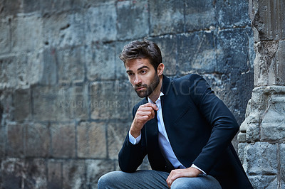 Buy stock photo Cropped shot of a handsome young businessman sitting in an urban alleyway