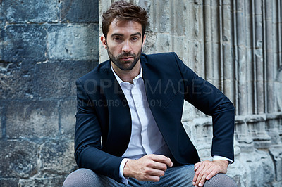 Buy stock photo Cropped portrait of a handsome young businessman sitting in an urban alleyway