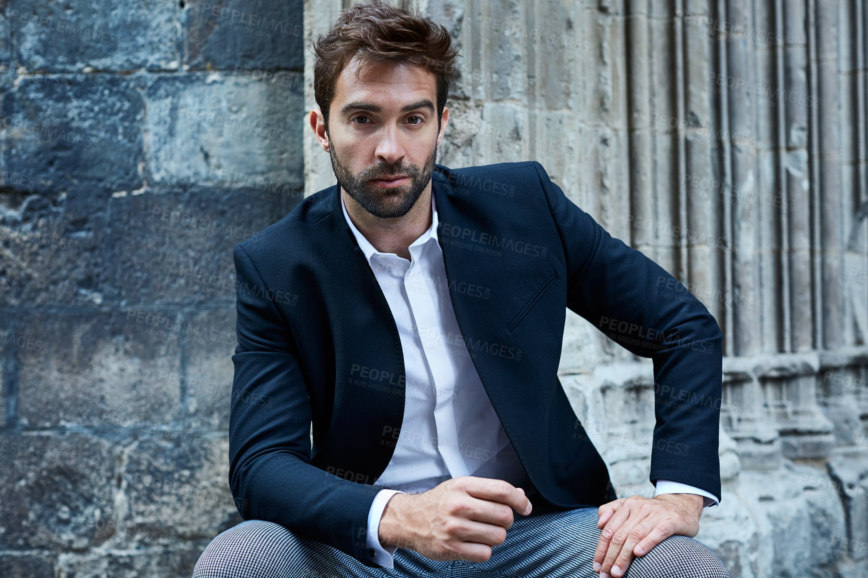 Buy stock photo Cropped portrait of a handsome young businessman sitting in an urban alleyway