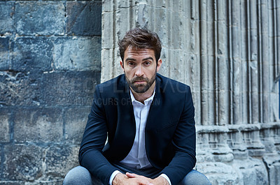 Buy stock photo Cropped portrait of a handsome young businessman sitting in an urban alleyway