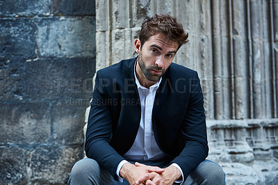 Buy stock photo Cropped portrait of a handsome young businessman sitting in an urban alleyway