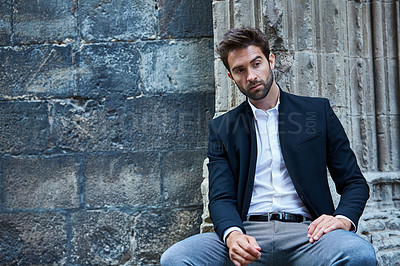 Buy stock photo Cropped shot of a handsome young businessman sitting in an urban alleyway
